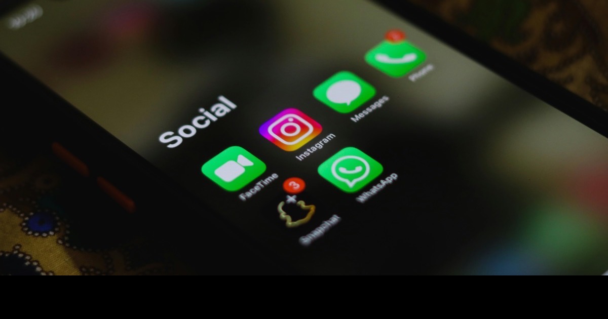 Person holding a smartphone with social apps on screen